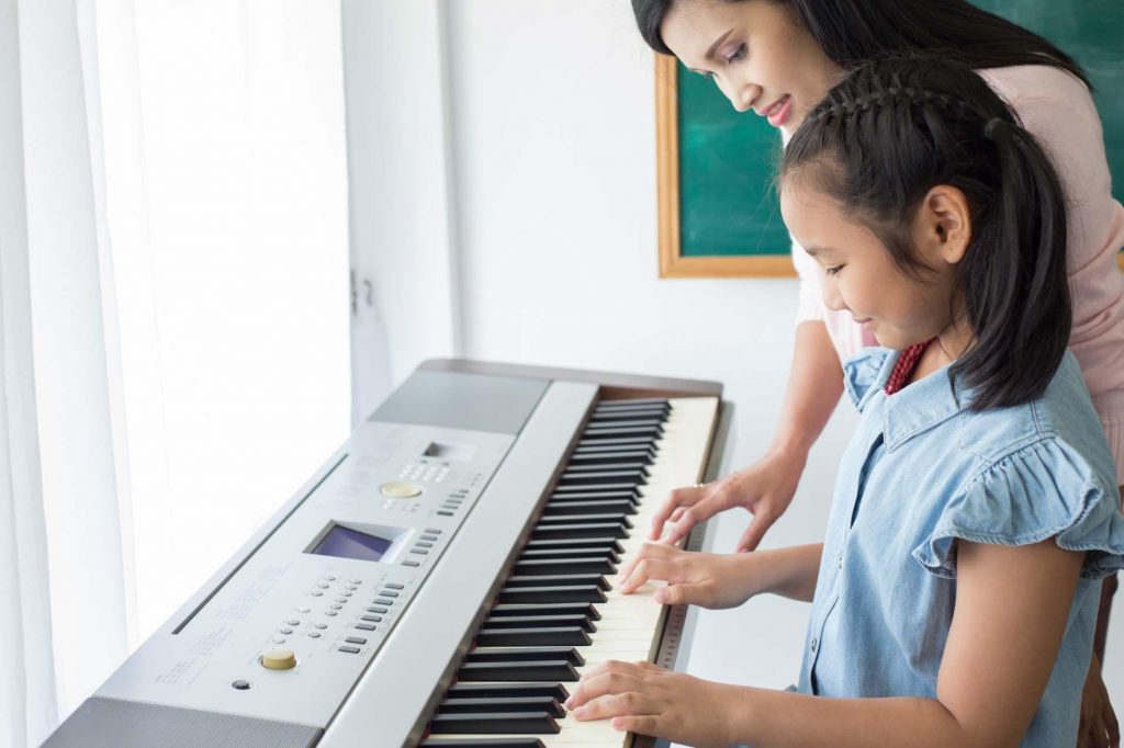 young girl learning to play the keyboard