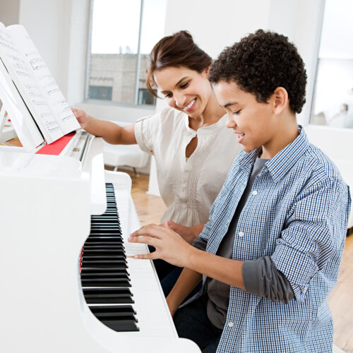 Woman giving piano lesson to boy